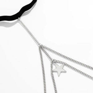 Detail of star pendant and layered silver metal chains on black elastic leg chain