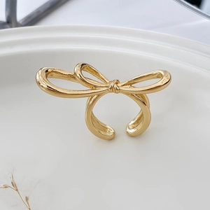 Detail of adjustable golden bow ring on white porcelain plate with floral accents