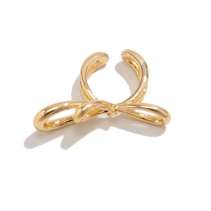 Macro shot of polished gold-plated bow-shaped ear cuff with minimalist metallic finish