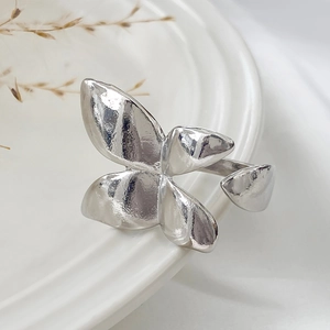 Close-up of a silver butterfly ring with hammered texture resting on a ceramic dish
