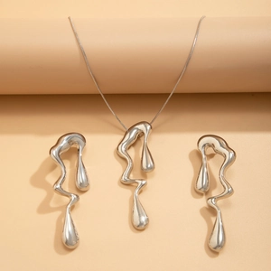 Dettaglio della collana in metallo liquido argento con orecchini a goccia coordinati