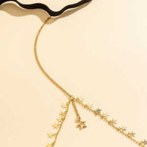 Close-up of golden star pendants on a delicate tassel leg chain with elastic band