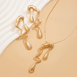 Dettaglio macro del set di collana e orecchini dorati con design in metallo liquido