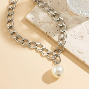 Detailed macro view of a large white pearl pendant on a thick silver chain necklace