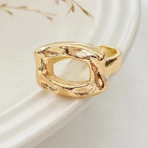 Detail of gold hammered texture on an irregular rectangular ring placed on white ceramic