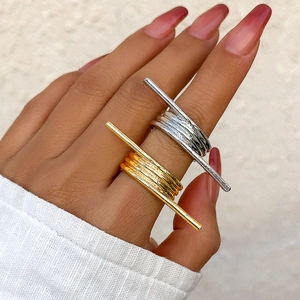 Close-up of gold and silver minimalist bar rings worn on fingers with metallic texture