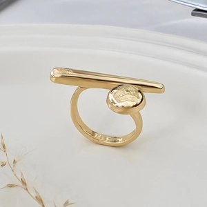 Macro detail of golden metal bow ring showing polished geometric texture and minimalist style