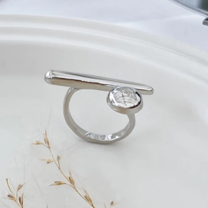 Macro shot of polished silver metal ring with a clear round crystal and geometric bow design
