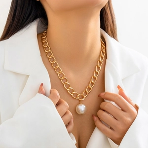 Gothic chunky gold chain necklace with large pearl pendant worn on white blazer