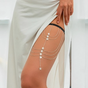 Detail of silver layered leg chain with star charms and elastic black thigh band