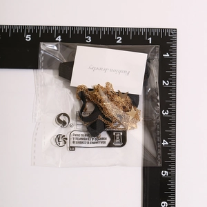 Detailed close-up of gold star charms and chains leg accessory in retail packaging