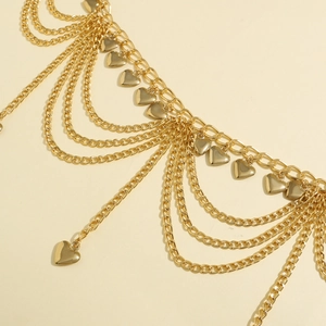 Detail of multilayer golden waist chain featuring polished heart charms and link chains