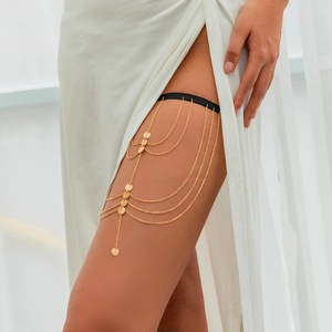 Detail of layered gold leg chain with metallic sequins and elastic thigh band
