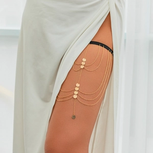 Detail of multi-layer gold leg chain with round sequins and black elastic band