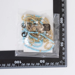 Detail of multi-layer beaded body chain with light blue seed beads and pearls in packaging