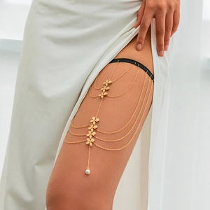 Close-up of gold layered thigh chain with metal flowers and elegant pearl pendant