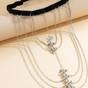 Detail of layered silver leg chain with floral pendants on elastic black band strap