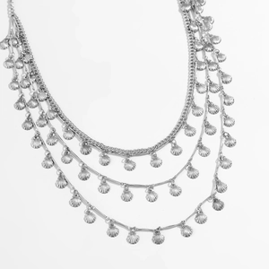 Vue détaillée d'une chaîne de taille argentée multicouche avec des pendentifs coquillages