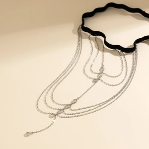 Detail of wave-edge black elastic thigh chain with layered silver metal fringe and crystals