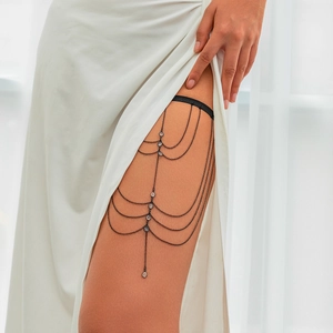 Detail showing multi-layer black metal tassel leg chain with sparkling crystal accents