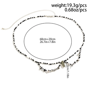 Détail de la chaîne de taille avec perles noires et blanches et pendentif en pierre