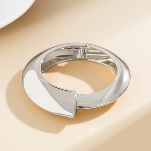 Dettaglio di un bracciale rigido argento lucido con design geometrico e cerniera