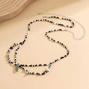 Détail de la chaîne de corps multicouche en perles noires et blanches et pendentifs