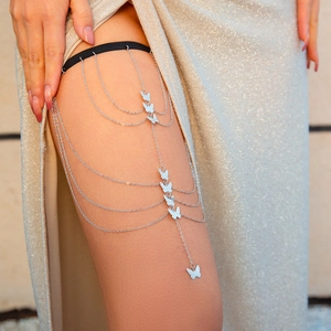 Detailed macro view of black elastic leg chain with silver butterfly charms and chains