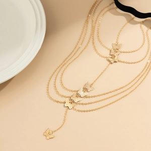 Detail of layered gold leg chain featuring butterfly charms and black elastic band