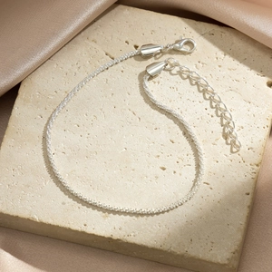 Close-up of sparkling silver multilayer chain with lobster clasp and teardrop pendant