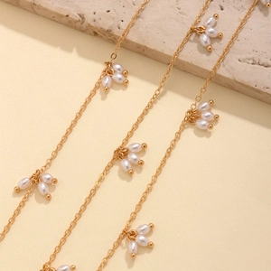 Détail d'un collier doré avec pendentifs en perles de riz à trois pétales sur pierre