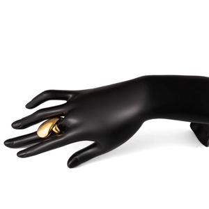 Détail d'une bague dorée forme lave liquide irrégulière sur un support main noir