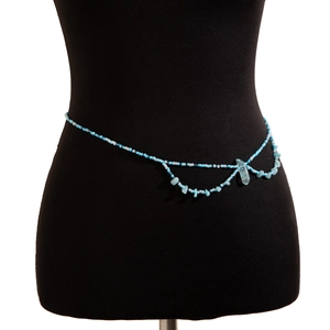 Détail d'une chaîne de taille bohème avec perles bleu clair et pendentif cristal sur mannequin