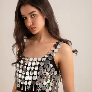 Detalle de lentejuelas metálicas plateadas en top de malla negra estilo body chain cyberpunk