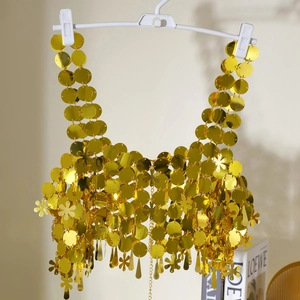 Detalle del top halter de lentejuelas doradas con anillos metálicos y dijes de flecos