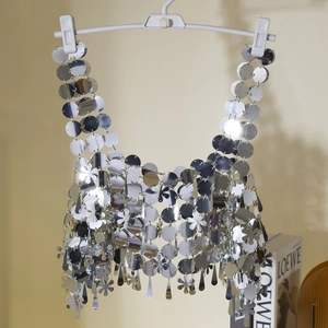 Detalle de lentejuelas metálicas plateadas y discos florales en una cadena de cuerpo club