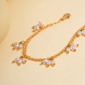 Vue détaillée du bracelet double chaîne doré orné de breloques en perles de riz élégantes