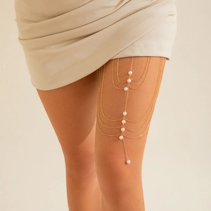 Detail of layered gold thigh chain with elegant white pearls on model for party wear
