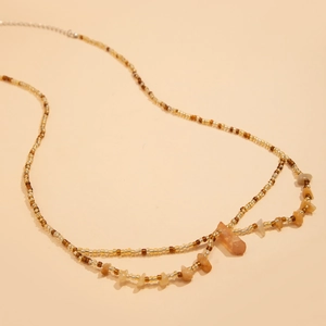 Détail de la chaîne de taille boho avec perles jaunes et pendentifs en citrine brute