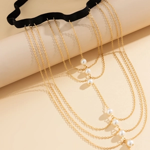 Detail of multi-layer gold leg chain with white pearls and elastic black thigh band