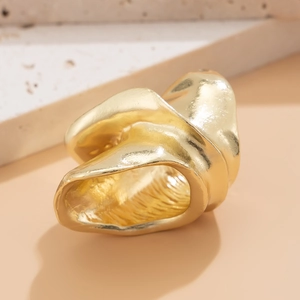 Vue macro d'une bague dorée irrégulière style lave sur pierre dans un décor épuré