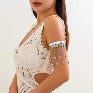 Λεπτομέρεια από ασημένια boho αλυσίδα μπράτσου με κρεμαστά νομίσματα και μακριά κρόσσια