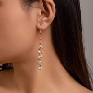 Longues boucles d'oreilles dorées avec perles de riz blanches et design de chaîne à glands