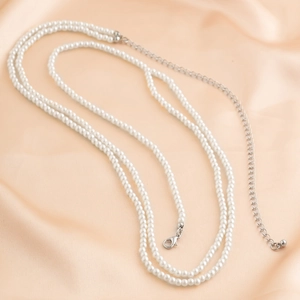 Détail d'une élégante chaîne de corps en perles double rang avec fermoir argenté sur satin