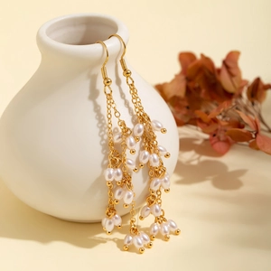 Détail de longues boucles d'oreilles dorées à pampilles et perles de riz de luxe