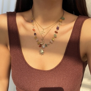 Λεπτομέρεια από boho κολιέ με πολύχρωμες πέτρες και χρυσό μενταγιόν σε σχήμα φεγγαριού