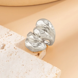 Gros plan d'une bague argentée style lave liquide avec une finition polie sur travertin