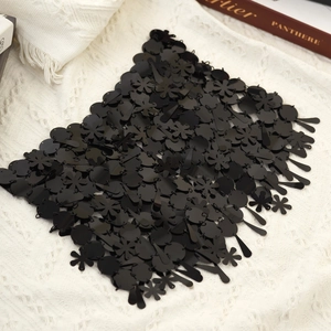 Detalle de cadena corporal de lentejuelas negras con diseños florales sobre tela blanca