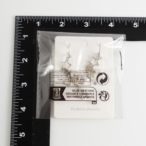 Gros plan de boucles d'oreilles étoile avec perle et règle sur un fond blanc