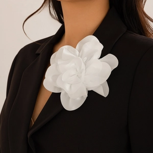 Detailansicht einer eleganten weißen Chiffon-Blumenbrosche am schwarzen Revers